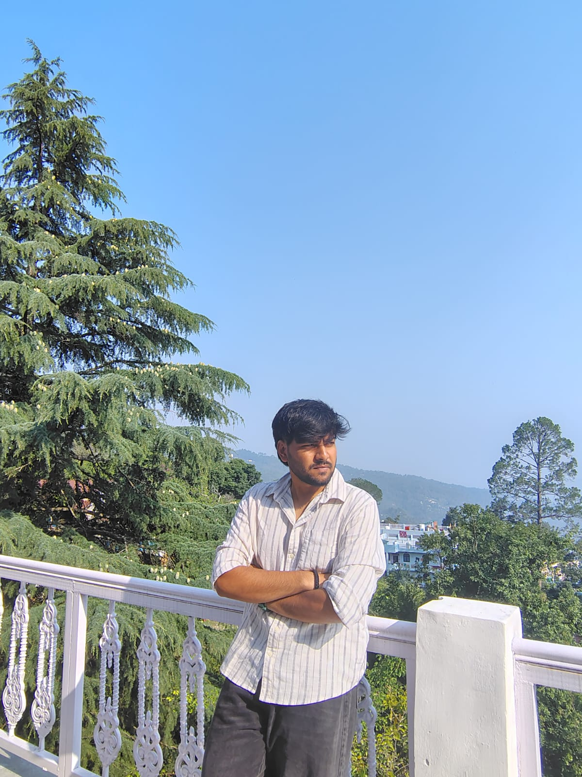 Asmit Rai standing on a terrace with trees and hills behind him